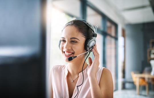 Customer Service Lady Talking Into Phone Headset At Computer.