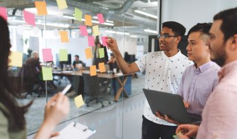 group meeting on a board with pink, orange and green sticky notes